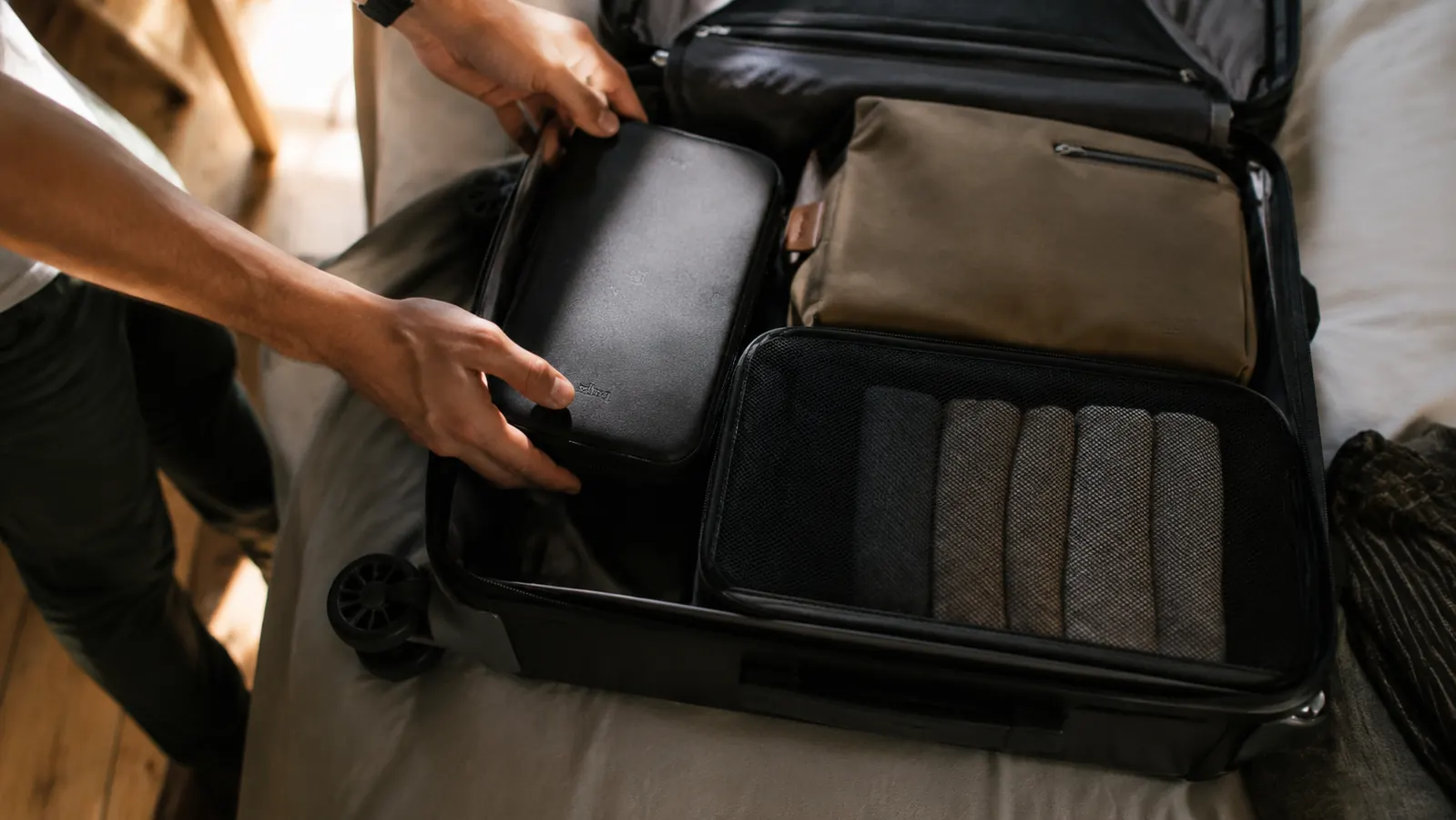 Electronics organizer packed inside a carry-on suitcase alongside a toiletry bag and packing cube
