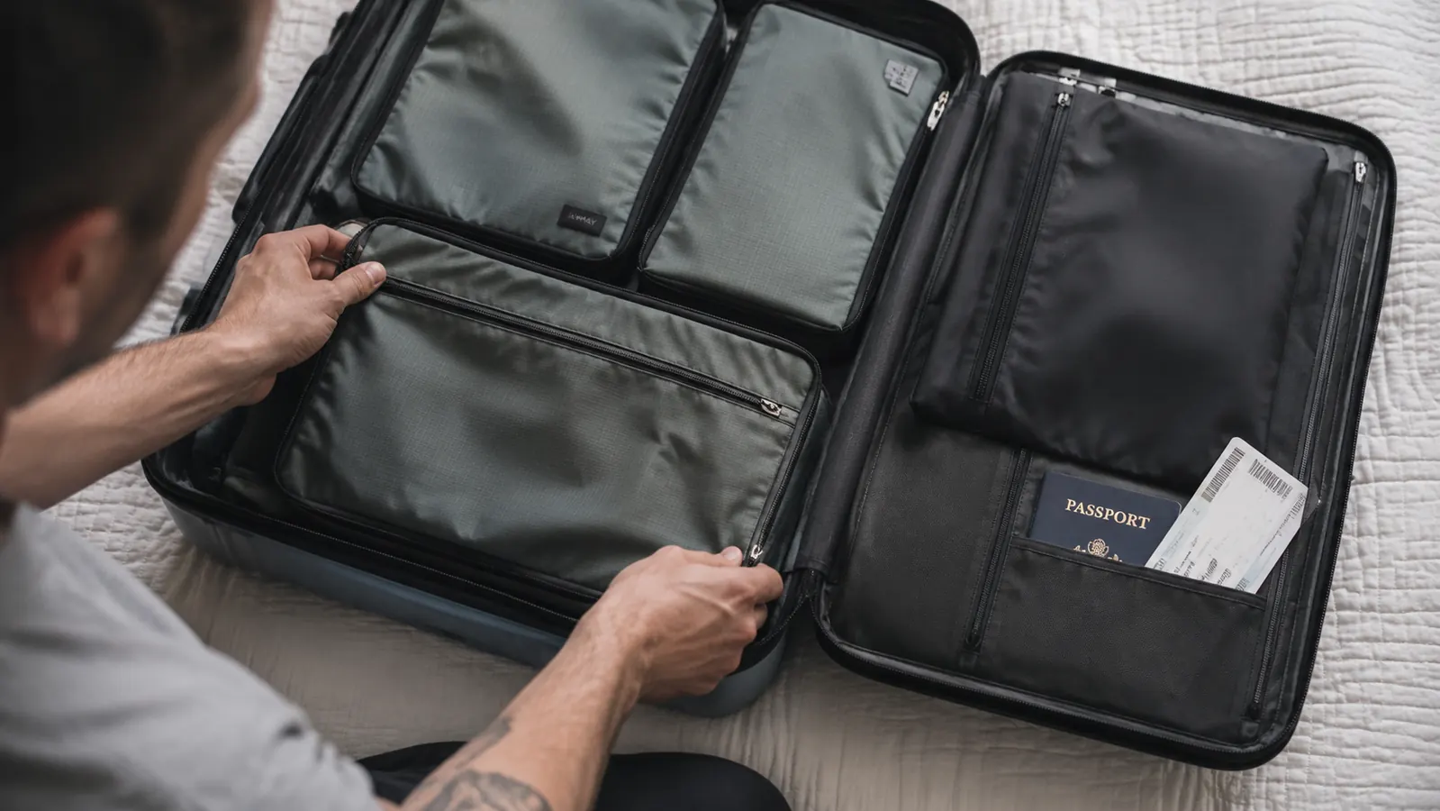Travel toiletry bag packed flat inside a carry-on suitcase beside packing cubes