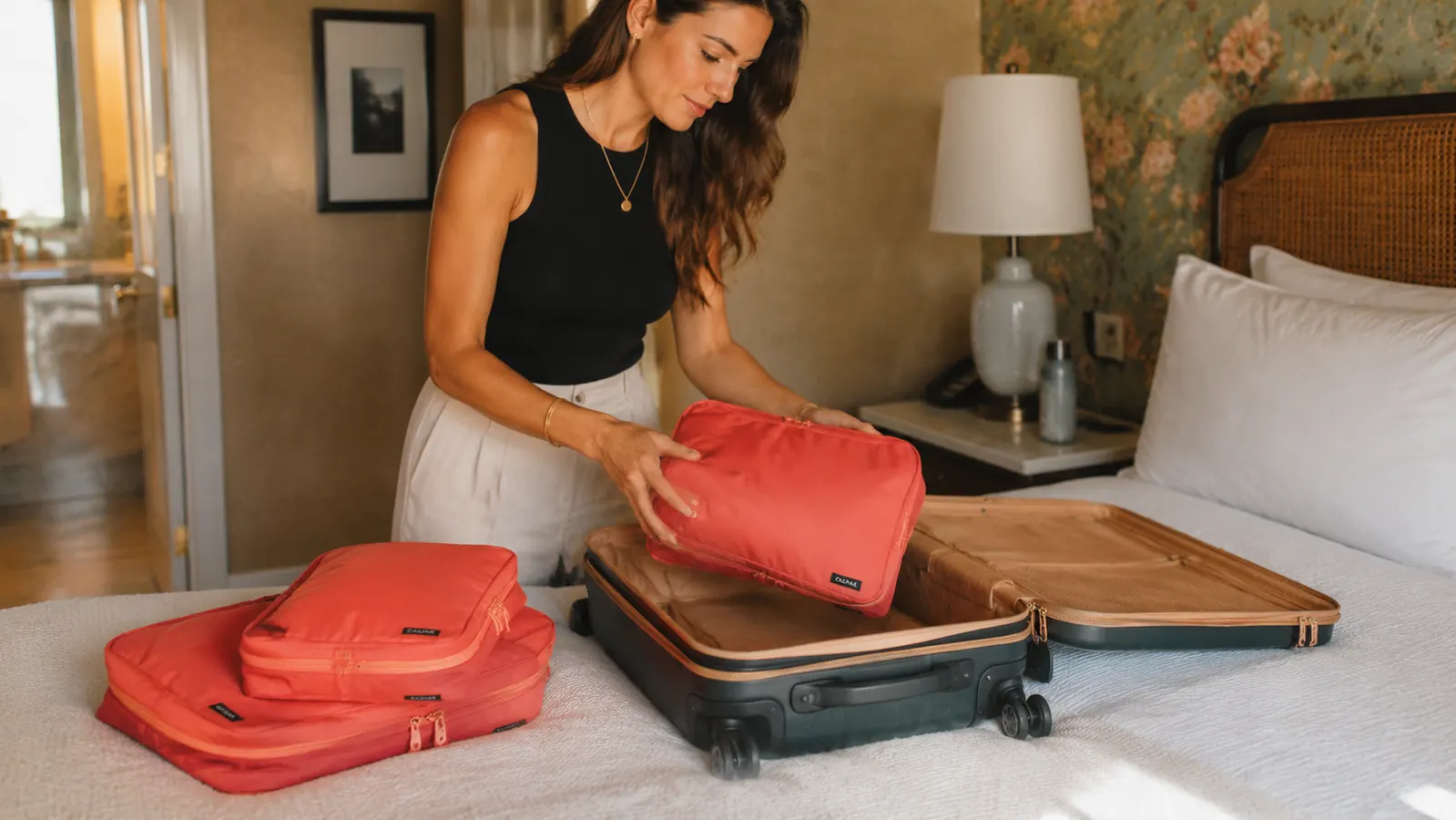 Traveler packing Veken cubes into a carry-on suitcase in a bright hotel room